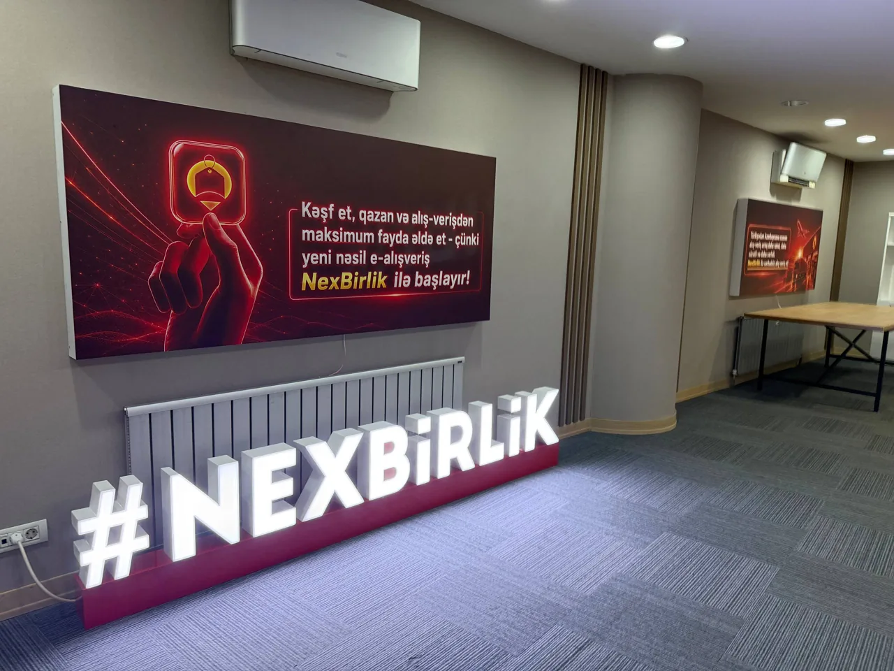 İşıqlı NexBirlik yazısı olan brend divarı